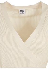 Ribbad beige topp med V-ringning, har en insvängd stil och slät textur. Etiketten säger "URBAN CLASSICS", storlek XS.