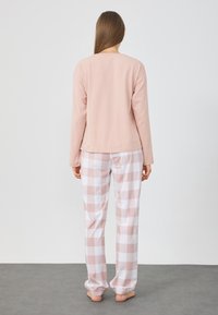 Langærmet pink top kombineret med ternede pyjamabukser i lyserød og hvid, der har en elastisk talje og indsnævrede manchetter.