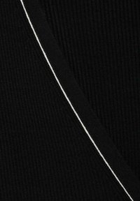 Tissu noir à côtes avec une couture blanche contrastante, mettant en valeur une coupe diagonale. La texture est douce et détaillée, soulignant la profondeur du matériau.