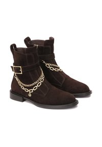 Botines de ante marrón con punta cuadrada, suela de goma plana y un acento de cadena dorada. Presentan un hebilla lateral y detalles de costura.