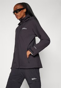 Dark gray waterproof jacket with adjustable hood, featuring two side pockets, a logo on the chest, and Velcro cuffs for secure fit.