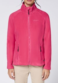 Pink fleece jacket with a high collar, full front zipper, and two side pockets featuring zippers. Smooth texture and fitted design.