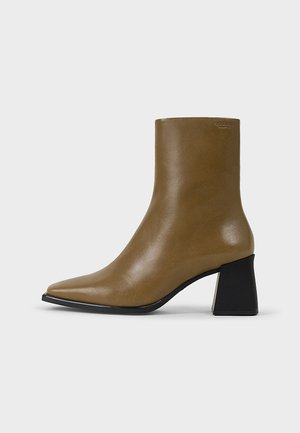 Brązowy skórzany botek za kostkę z ostrym noskiem, eleganckim kształtem i teksturowanym wykończeniem. Posiada kontrastowy czarny blokowy obcas.