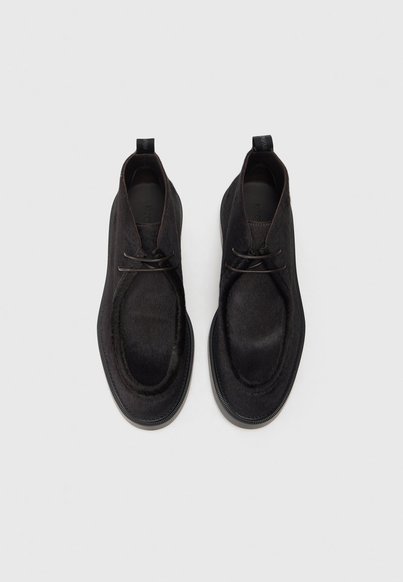 Sorte ankelstøvler lavet af glat læder med en rund tå, diskret stikninger og en tekstureret finish. Indeholder en trækløkke på hælen.