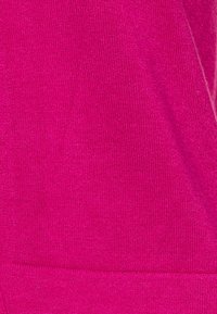 Tejido de punto de color rosa intenso, con una textura suave y un ligero brillo. Presenta un diseño sin costuras y un sutil borde acanalado en la parte inferior.