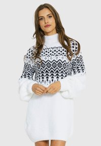 Biała swetrowa sukienka z wełny, z czarnym geometrycznym wzorem na górnej części, z długimi bufkami i wysokim kołnierzem.