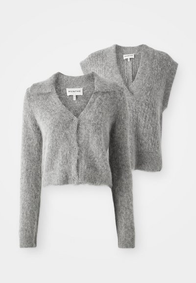 Pilkas trumpas megztinis iš pūkuotos medžiagos, su V formos iškirpte, mygtukų užsegimu ir trumpomis rankovėmis. Etiketė: MUNTHE.