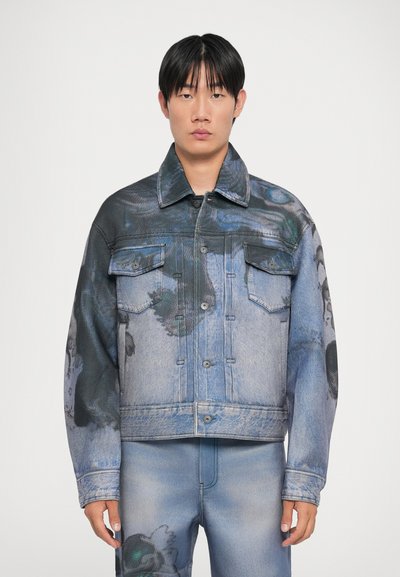 Denim jacket with a blue gradient, featuring abstract patterns in black and green. Button-up front, pointed collar, and two chest pockets.