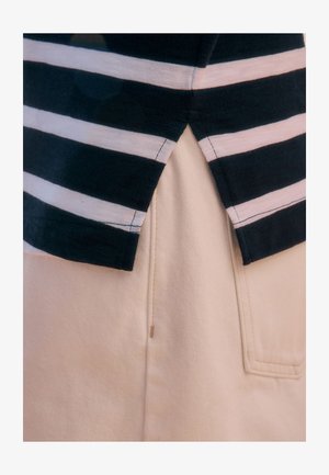 Marineblaue und weiß gestreifte Stoffoberteil mit geteiltem Saum, überlagert von einem hellbeigen Baumwollmischgewebe-Unterteil mit einer Taschenapplikation.