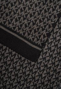 Tissu tricoté noir et gris à motif géométrique avec une finition texturée, complété par une bande côtelée noire unie.