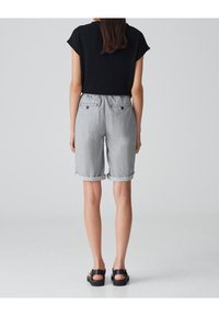 Black short-sleeve top and gray striped shorts with rolled cuffs, featuring an elastic waistband and back pockets with button accents.