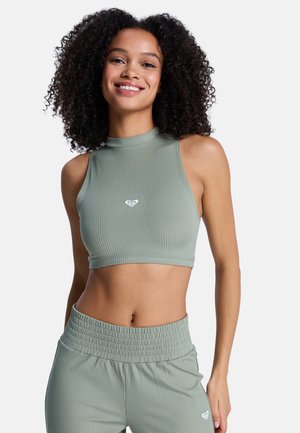 Top court côtelé en vert doux avec un col montant et un petit logo blanc sur la poitrine. Associé à un pantalon assorti à taille élastique.