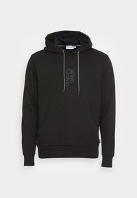 Felpa nera realizzata in morbido materiale, con una tasca a marsupio frontale, cordini grigi e un logo discreto sul petto.