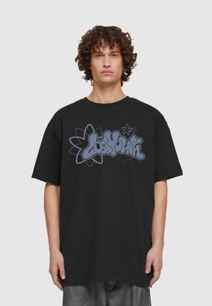 Svart oversized t-skjorte med blå grafisk trykk med teksten "Lost Youth" blant blomster- og stjernemotiver. Laget av bomull, kortermet.