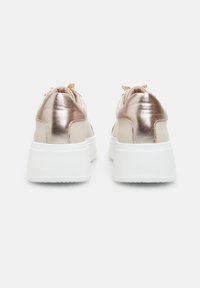 Sneakers beige con accenti in oro rosa metallico, parte superiore in morbida pelle, suola spessa bianca e lacci decorativi nella parte superiore.