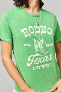 Zöld pamut póló fehér, kopott grafikával, melyen a "RODEO Texas Fort Worth" felirat és csizmadizájn látható. Kerek nyakkivágású, rövid ujjal.
