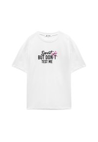 Witte katoenen t-shirt met korte mouwen, met zwarte tekst "Sweet BUT DON'T TEST ME" en een roze strikgraphic aan de linkerkant.