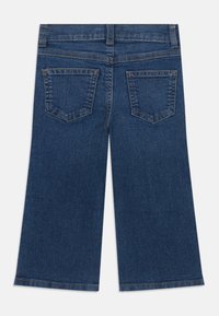 Jeans anchos de mezclilla en un tono azul oscuro. Presentan dos bolsillos traseros y costuras doradas a lo largo de las costuras.