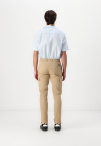 Lichtblauw T-shirt met korte mouwen, khaki cargo broek met elastische taille en zijzakken, en zwarte sneakers. Eenvoudig, ademend ontwerp.