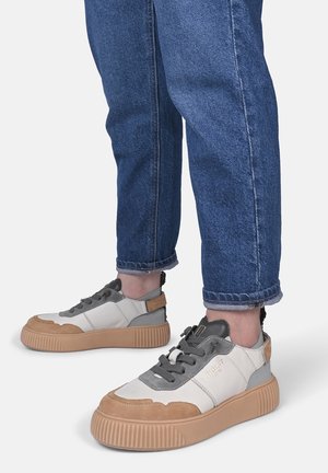 Sneaker bianchi e grigi con accenti color panna, punta testurizzata e suola spessa a righe; allacciate con una linguetta grigia e un passamano sul tallone.
