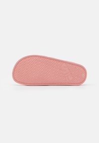 Suola di scarpa in gomma rosa con superficie testurizzata, caratterizzata da un motivo a spina di pesce e un dettaglio del logo impresso sul lato.
