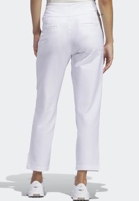 Vita, åtsittande byxor med en slät textur och elastisk midja. Har två bakfickor och slitsöppningar vid fållen.