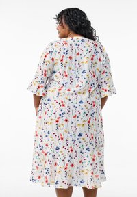 Blumenkleid in Midi-Länge mit kurzen ausgestellten Ärmeln, auf einem weißen Hintergrund mit bunten Mustern aus roten, blauen und gelben Blumen.