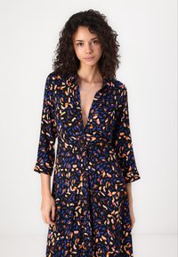 Black dress with a colorful abstract pattern in orange, blue, and purple. Features a collar, button-down front, and three-quarter sleeves.