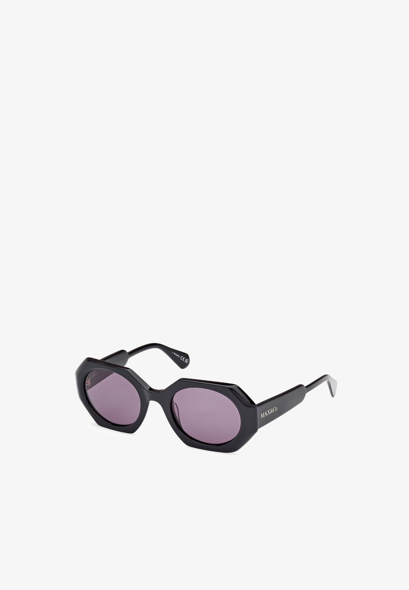 Gafas de sol octagonales negras con lentes morados, montura gruesa y brazos elegantes. Marca destacada en el lateral. Textura suave en toda la superficie.