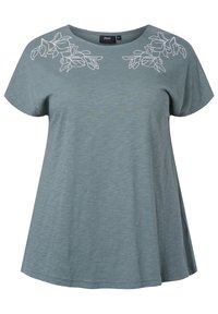 Ljusblå kortärmad blus med lös passform och vita blommönster nära den rundade halsringningen på båda axlarna.