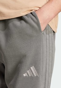 Gr�å sweatpants lavet af en bomuldsblanding, med en tekstureret overflade, sidelomme og et sølvbroderet logo på venstre lår.