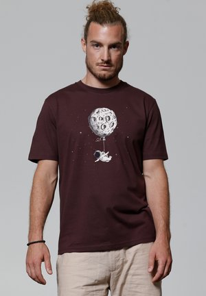 Bordeaux katoenen T-shirt met een grafisch ontwerp van een astronaut die een ballon vasthoudt in de vorm van de maan, met sterren op de achtergrond.