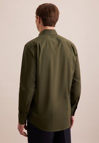 Camicia verde a maniche lunghe con colletto a punta, polsini con bottoni e un tessuto leggero e liscio. Presenta una schiena dritta e una vestibilità rilassata.