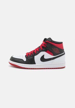 Chaussure de sport montante mi-haute en cuir noir, blanc et rouge. Dotée de lacets rouges, d'un swoosh noir et d'un accent rouge sur le talon avec un détail de logo.