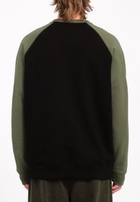 Sweatshirt noir avec des manches raglan vert olive, présentant un col rond et un tissu texturé. Le dos est entièrement noir avec des poignets côtelés.