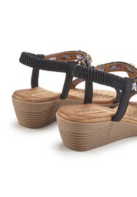 Zwarte plateau-sandalen met gestructureerde buitenzool, elastische banden en een gevoerde binnenzool. Heeft een geweven detail op de enkelband.