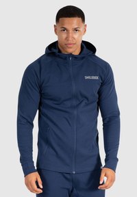 Felpa con zip blu navy realizzata in tessuto liscio, dotata di cappuccio, maniche a raglan e dettaglio del logo sul petto. Resistente e con tasche laterali.