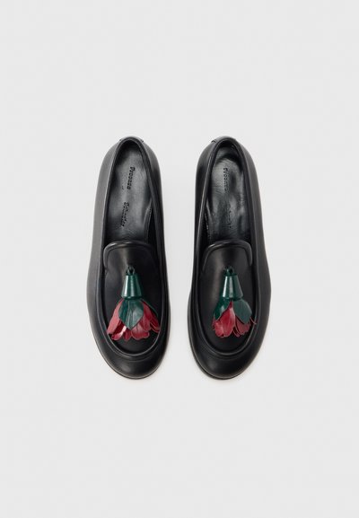 Mocassins pretos em couro com um adorno floral em couro vermelho e verde. Textura lisa com design de bico arredondado.