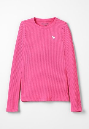 Prążkowana koszula z długim rękawem w jasnym różowym kolorze, wykonana z miękkiego materiału. Posiada okrągły dekolt oraz małe białe logo na lewej piersi.