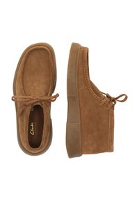 Brown suede shoes with a round toe, lace-up design, and rubber soles. Features stitched detailing and a soft texture.