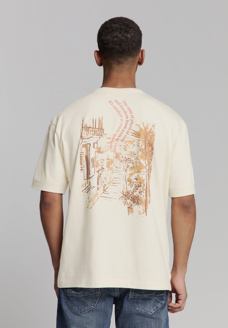 Crème-kleurig t-shirt met korte mouwen en een lichtbruine grafische print van een straatbeeld en tekst op de achterkant. Casual pasvorm.