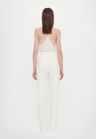 White jumpsuit featuring a flowing satin top with gathered back detail and wide-leg pants. Smooth texture and minimalist design.
