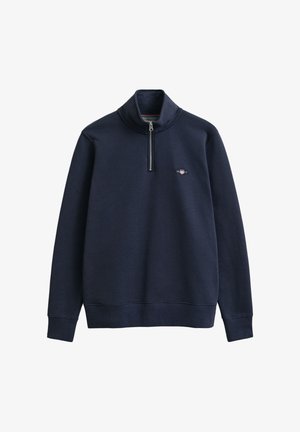 Sudadera azul marino con cuello alto, cierre de media cremallera y puños acanalados. Presenta un pequeño logotipo en el pecho. Tejido de textura suave.