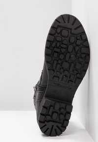 Bottine noire avec une semelle en caoutchouc texturé, fermeture éclair et détails de couture subtils. Taille 37 indiquée sur la semelle.