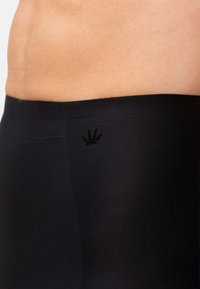 Elastico senza cuciture nero con logo corona ricamato. Texture morbida e liscia con finitura opaca, progettata per comfort e flessibilità.