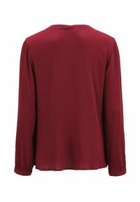 Maglia a maniche lunghe bordeaux, tessuto testurizzato con sottili pieghe verticali, scollatura rotonda e maniche con polsini. La vista posteriore mostra una vestibilità rilassata.