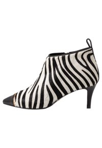 Zebra-print enkelboot gemaakt van textuurvacht. Heeft een spitse neus en zwarte leren accenten, met een slanke stilettohak.