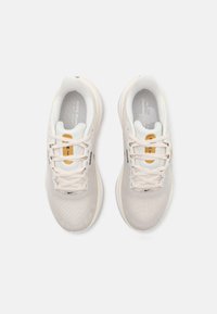 Lichtbeige sportschoenen met een bovenwerk van mesh, gewatteerde kraag en witte zolen. Kenmerken zijn onder andere fijne stiksels en een subtiel Nike-logo.