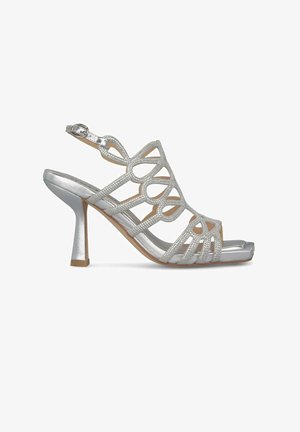 Silberne High-Heel-Sandale mit ausgeschnittenem Design und Strassakzenten. Verfügt über einen Knöchelriemen und eine eckige Zehenpartie. Glänzende Oberfläche sorgt für Kontrast.