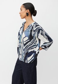 Camicia a maniche lunghe in blu navy e crema con motivo marmorizzato; presenta un scollo a V e una vestibilità comoda, abbinata a pantaloni in jeans scuri.